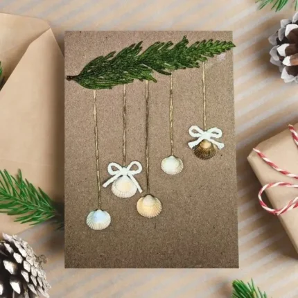 Handmade-Christmas-card-made-of-seashells-hanging-on-green-bench